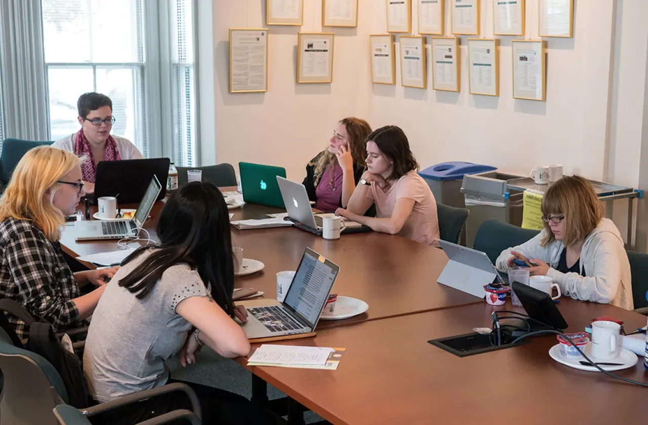 学生 gathered around a table in the Kahn colloquium room