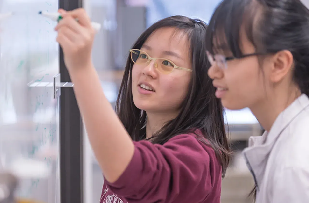 Two students writing on the whiteboard